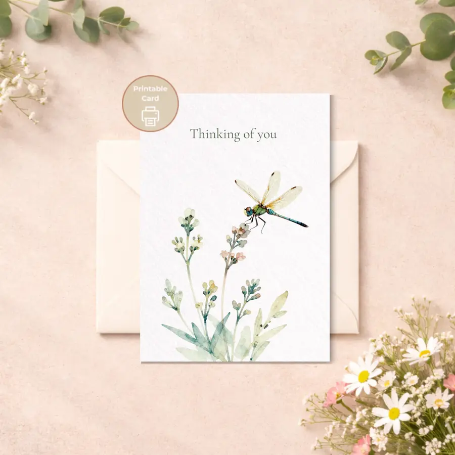 Styled product mockup: A printable thinking of you card with a delicate dragonfly, soft botanical stems, and muted green lettering on a black background.